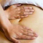 closeup of a woman having a massage at her abdomen.